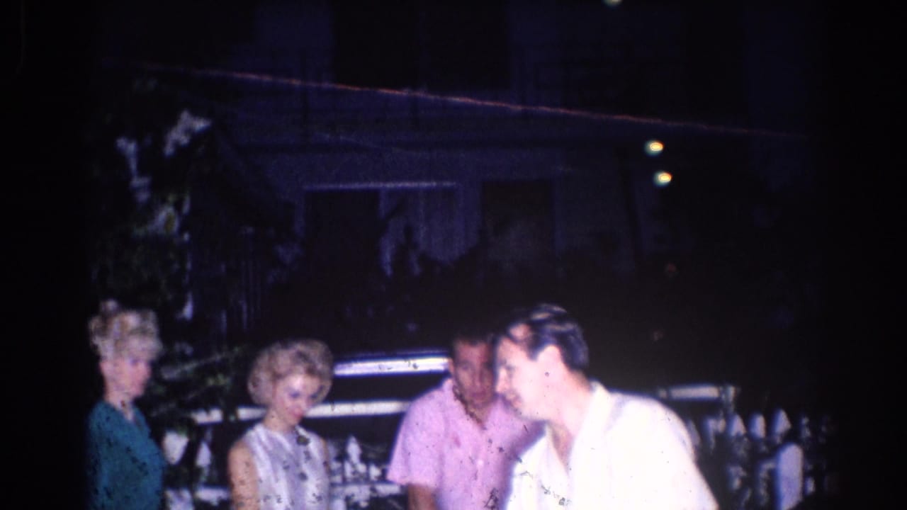 1966 El Monte home-movie frame showing adults gathered outdoors at night, including a woman in a light dress and a man in a pink shirt.