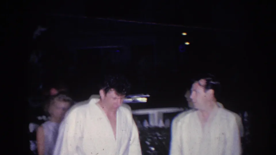 1966 El Monte frame showing men in light robes or open garments standing in a dim nighttime gathering.