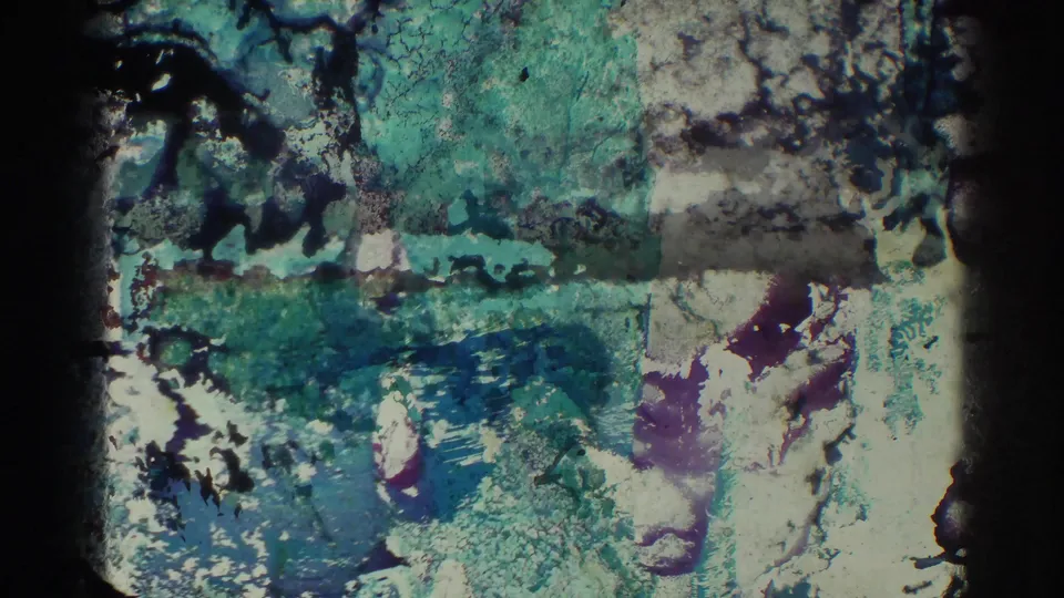 The final 8mm frame shows heavy physical-film damage, with green-blue color bleed, scratches, and partially obscured image detail.