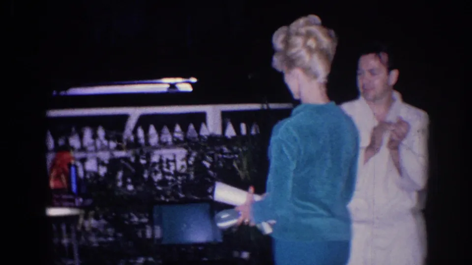 1966 El Monte home-movie frame showing adults greeting and talking in a lit backyard area at night.