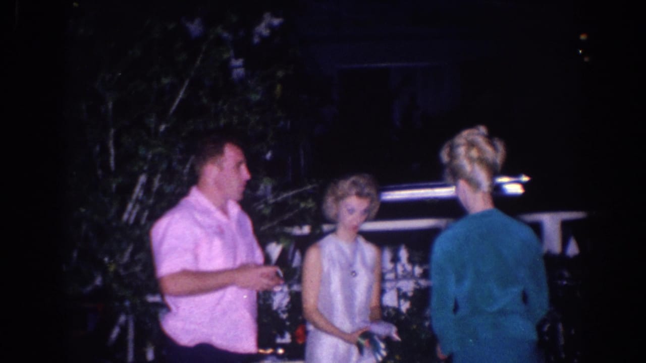 In 1966 El Monte home-movie footage, a man in a pink shirt talks with two women outdoors at night near a railing.