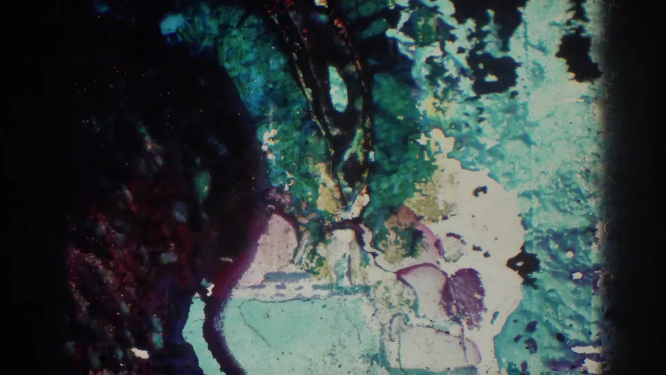 Damaged or transitional 8mm frame with mottled color, heavy exposure shift, and little identifiable scene detail.
