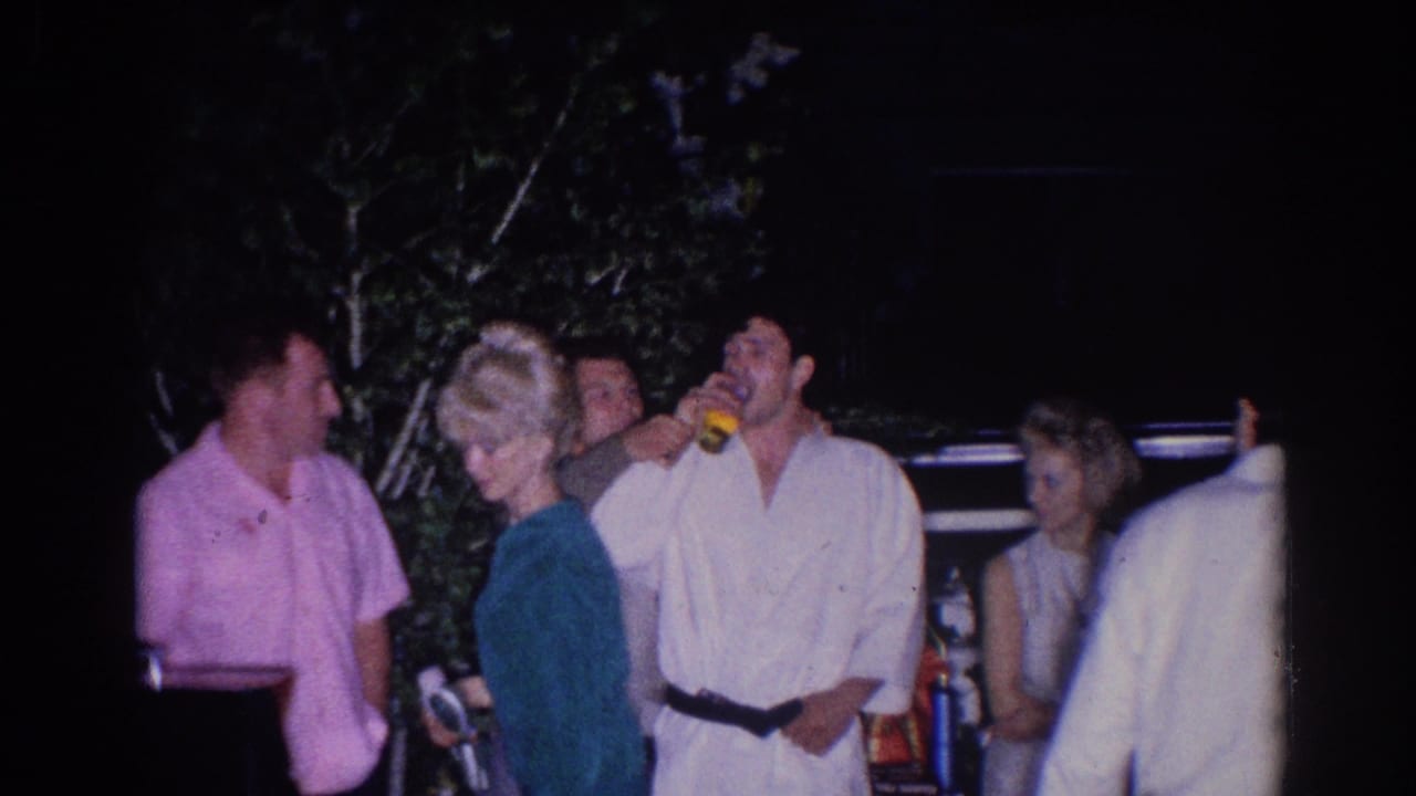 Adults stand outdoors at night near judo athletes, with one man drinking from a yellow cup.