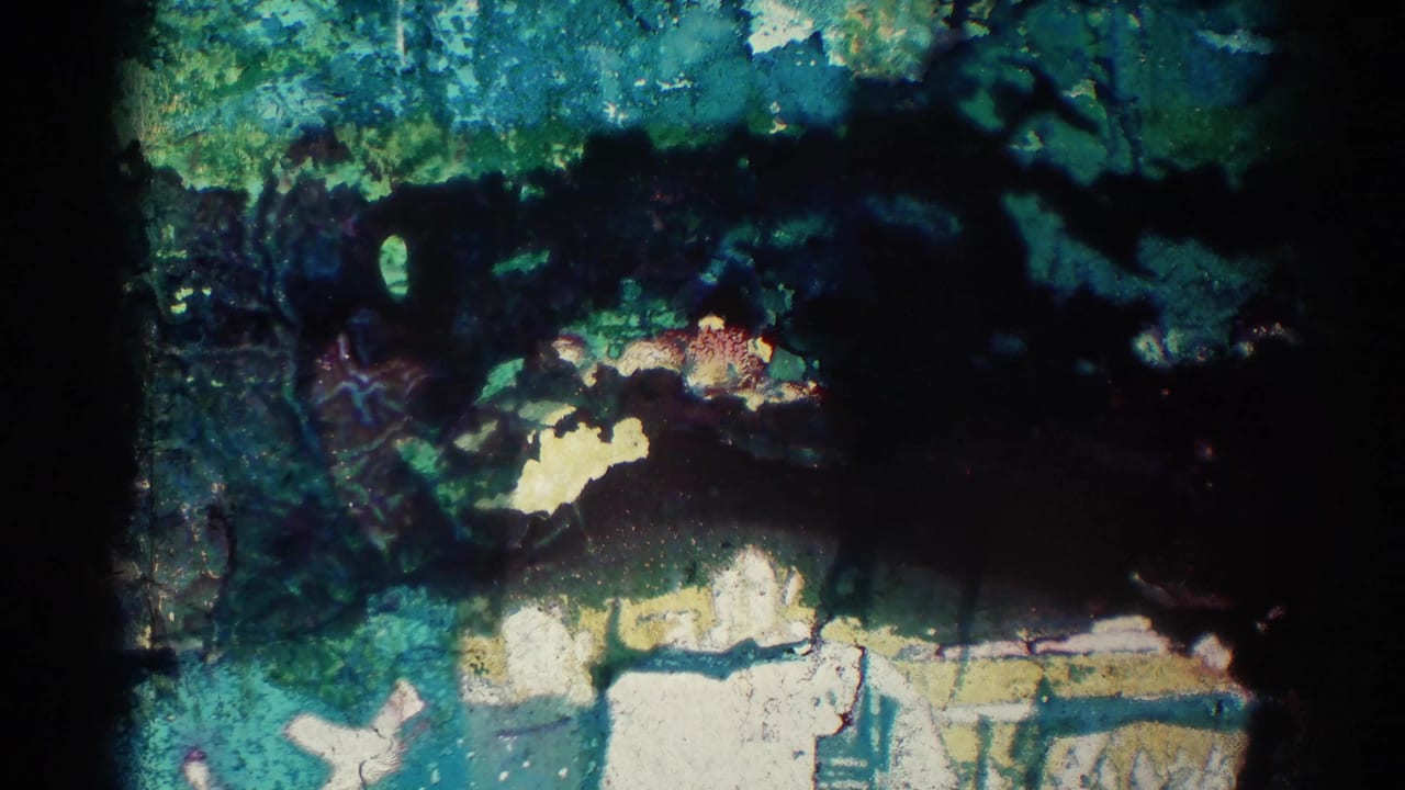 Dark, damaged or overexposed film area with partial outdoor shapes and color shifts.