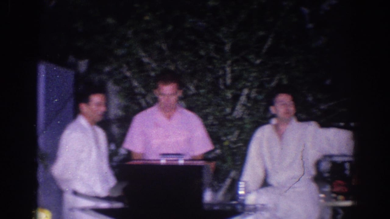 In a 1966 El Monte home-movie frame, three adult men stand outside near a table as a casual karate demonstration or party scene begins.