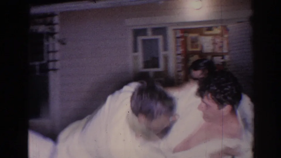 Several adults in white gi cluster near a house entrance during the nighttime El Monte karate demonstration, with faces partly visible.