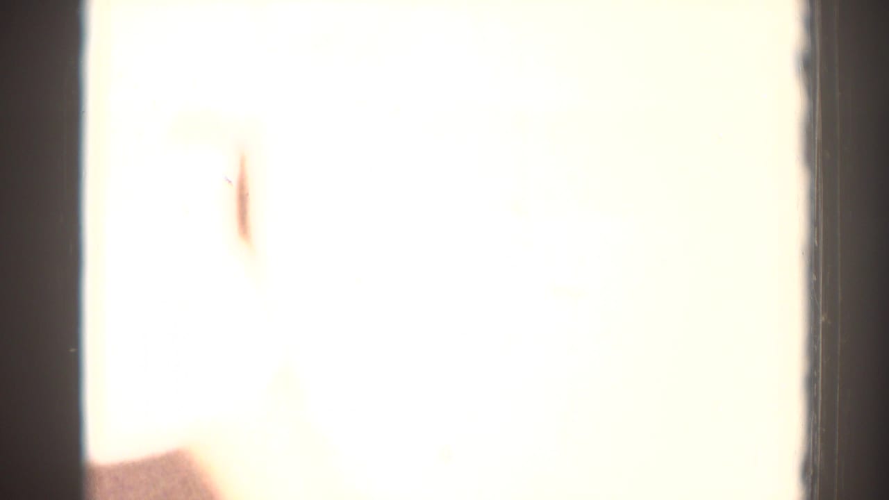 Overexposed 8mm frame from the El Monte clip with only faint interior detail and a partial figure visible.