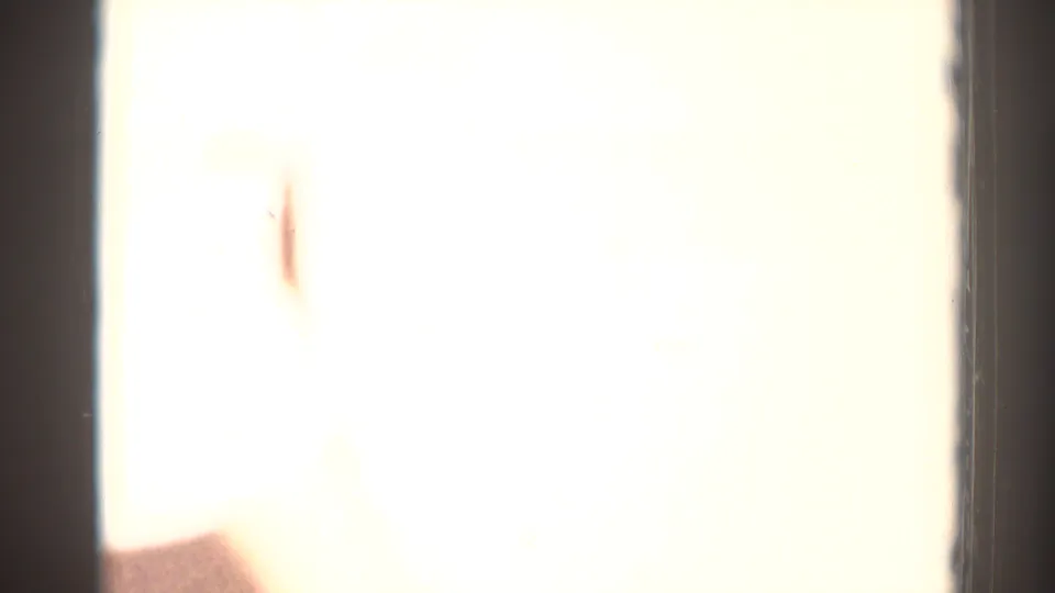 Overexposed 8mm frame from the El Monte clip with only faint interior detail and a partial figure visible.