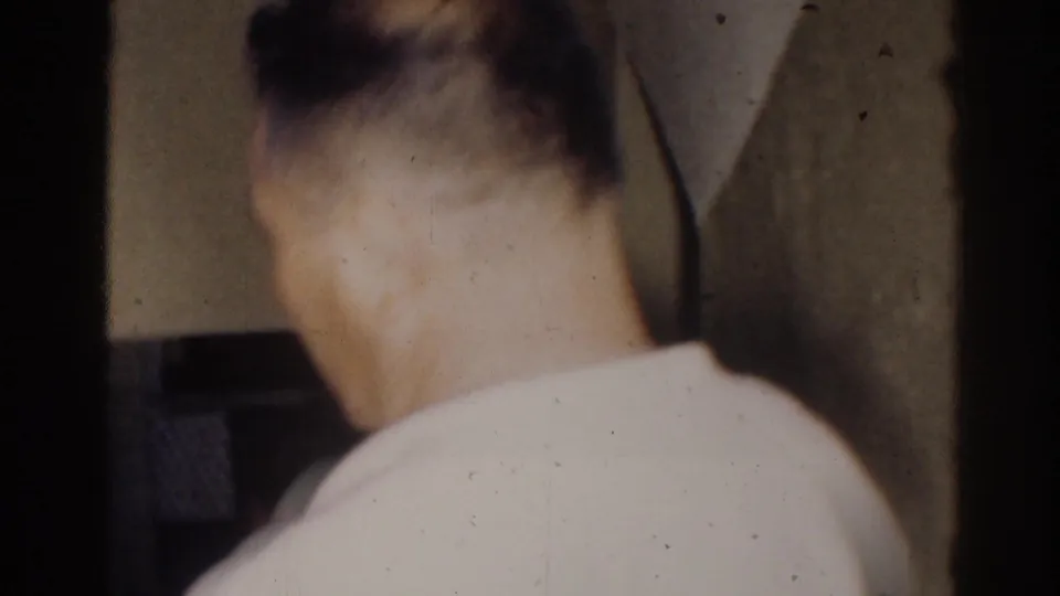 1966 El Monte frame showing a young martial arts student in a white uniform from behind inside a dim hallway.