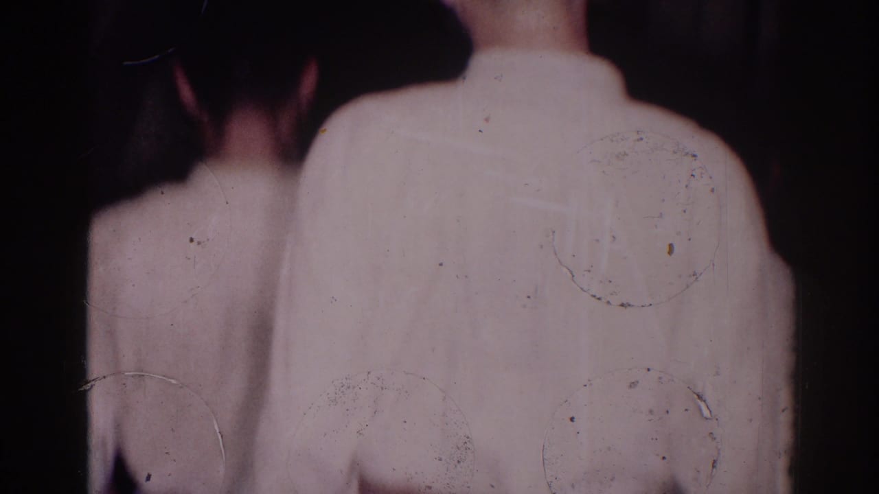 In 1966 El Monte footage, two judo athletes in white gis are seen from behind as they move through a dim indoor space.