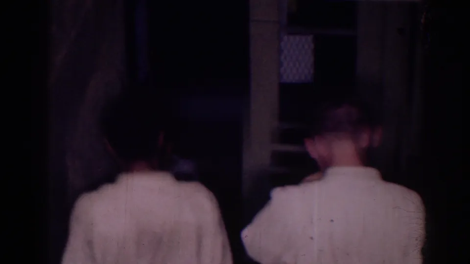Two judo athletes in white gis move away from the camera toward a doorway in the supplied 1966 El Monte home-movie footage.
