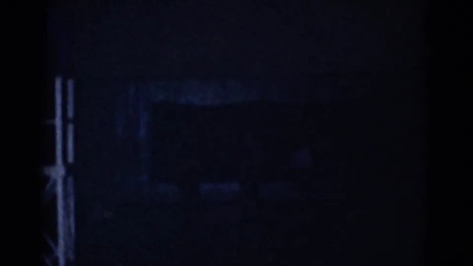 The final frame is mostly dark, with faint interior outlines and film grain visible as the scene falls into low exposure.