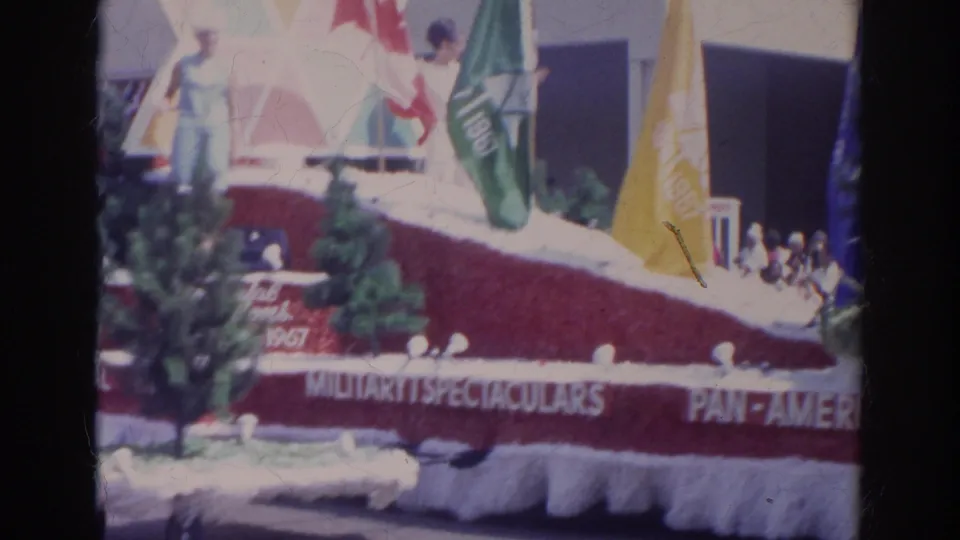 1966 Norfolk parade footage showing an angled float with flags, trees, red drapery, and partial military spectaculars wording.