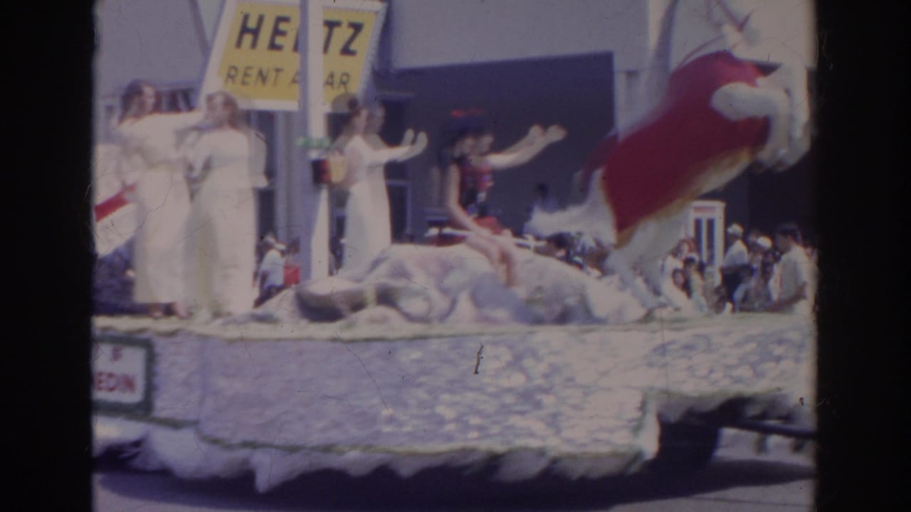 Women in white outfits wave from a decorated float during the 1966 Norfolk parade, with a Hertz sign and spectators behind them.