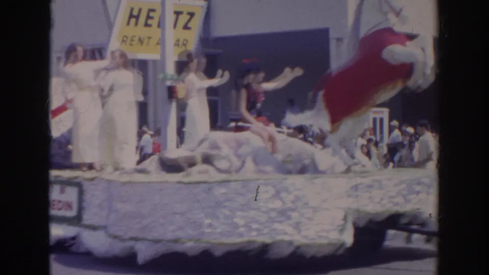 Women in white outfits wave from a decorated float during the 1966 Norfolk parade, with a Hertz sign and spectators behind them.