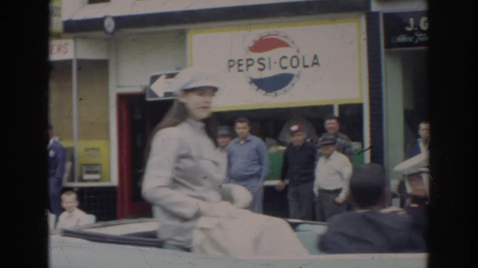 A rider in light clothing passes spectators in front of a Pepsi-Cola sign during the 1966 Norfolk parade.