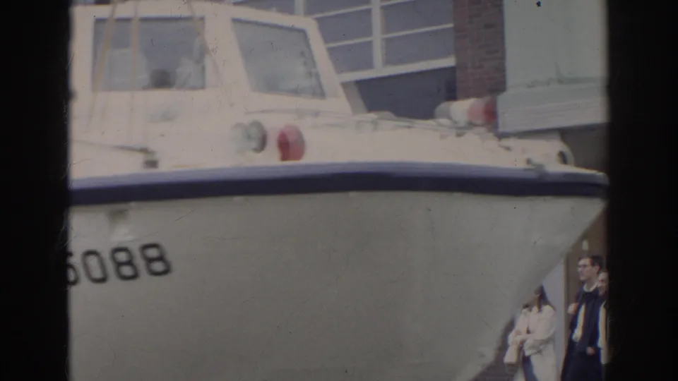 White amphibious duck boat in Norfolk, marked with visible numbers, with pedestrians standing near a building.