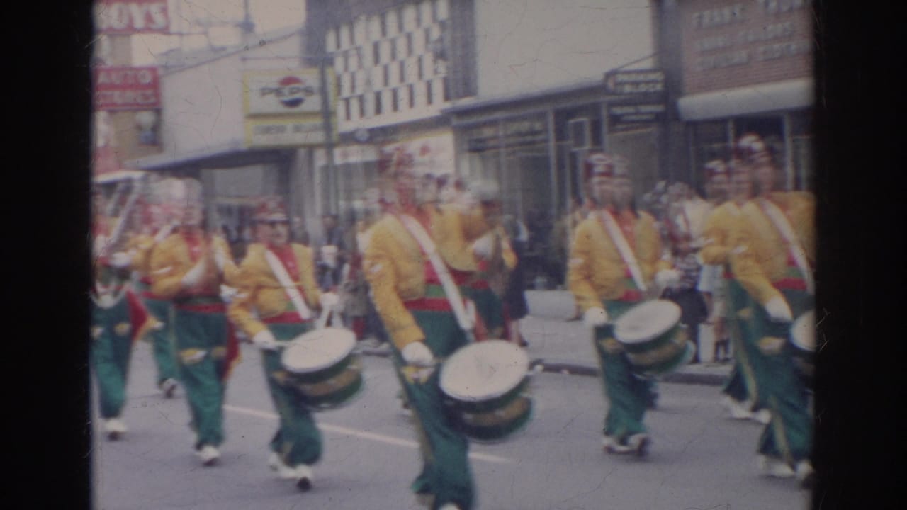 1966 Norfolk parade footage shows drummers in yellow jackets, red shirts, and green trousers marching past downtown storefronts.