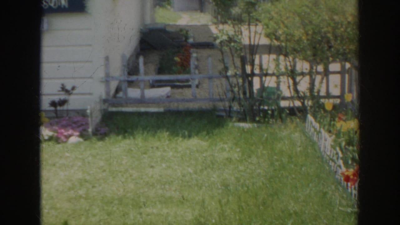 The final frame looks across the side yard toward flowers, shrubs, small steps, white siding, and a low white fence in the Norfolk residential scene.
