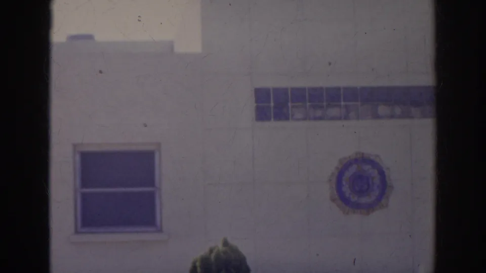 Norfolk 1966 footage shifts to the building wall near the lounge sign, showing windows, a round emblem, and partial signage at the edge.