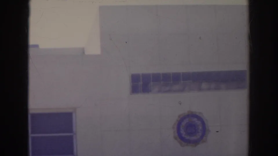 1966 Norfolk home-movie frame showing part of the American Legion Post 273 exterior with blue tile accents and a circular emblem.