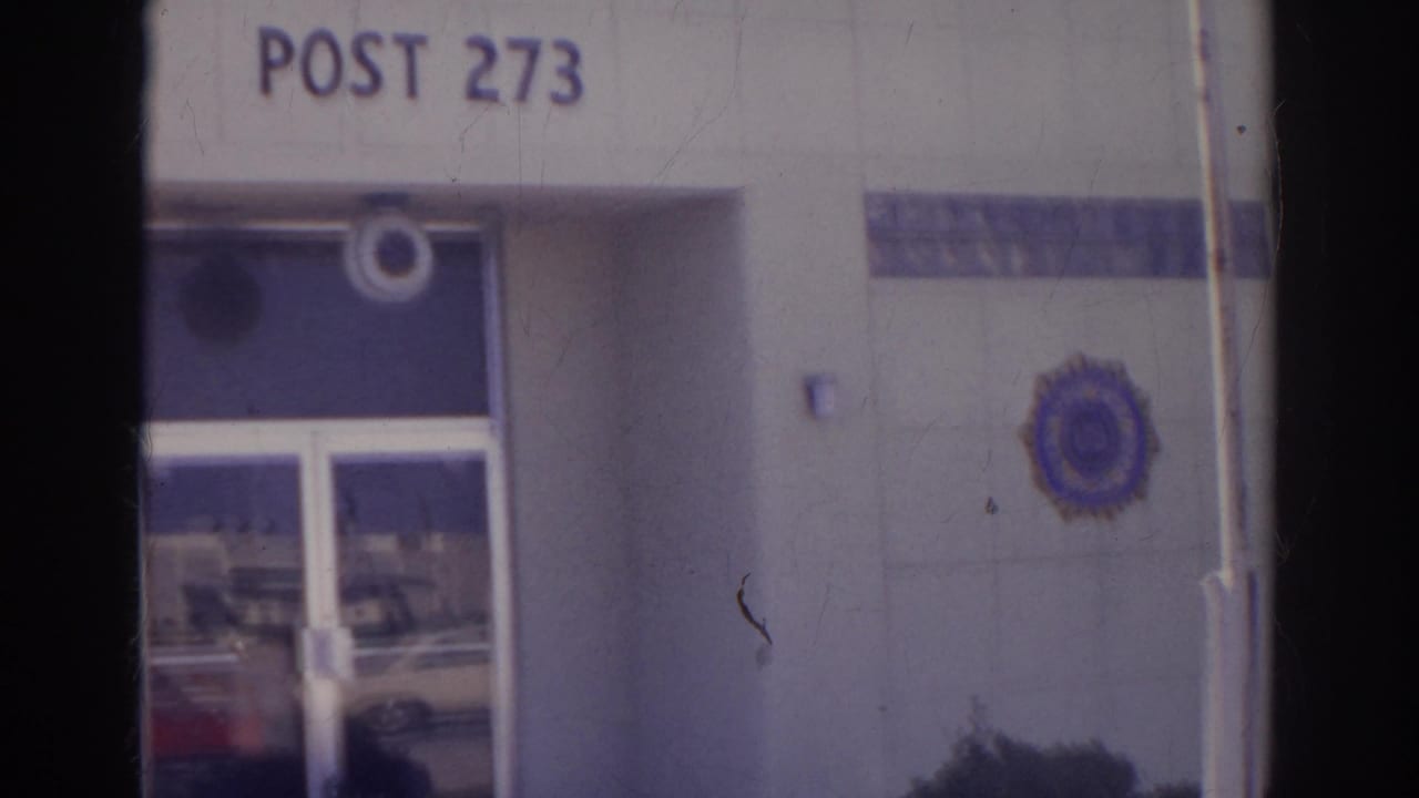 Norfolk 1966 view of Post 273 signage, the entrance doors, and a blue and gold American Legion emblem on the exterior wall.