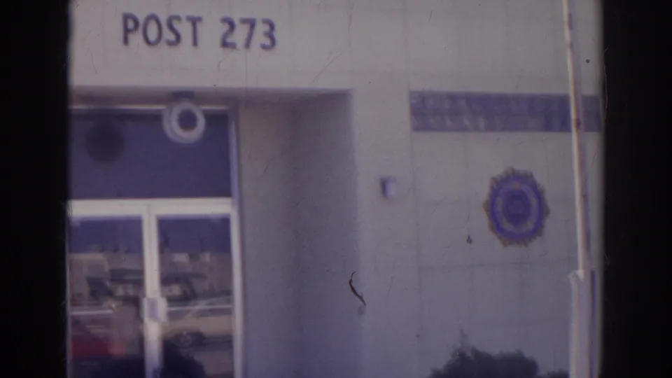 Norfolk 1966 view of Post 273 signage, the entrance doors, and a blue and gold American Legion emblem on the exterior wall.