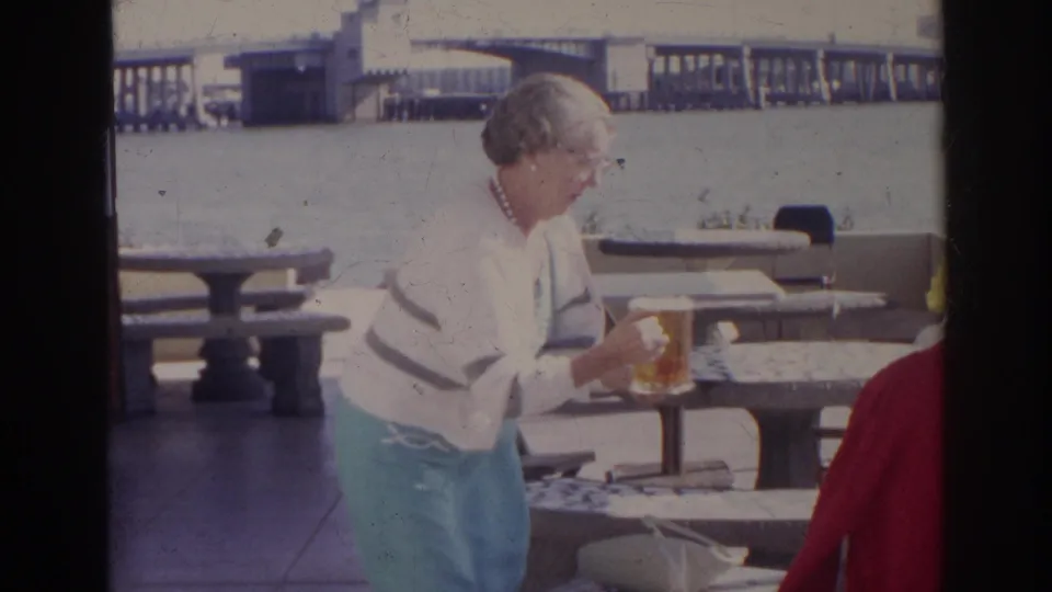 The woman appears to set a large beer glass on or near a stone picnic table at a Norfolk waterfront picnic area in 1966.