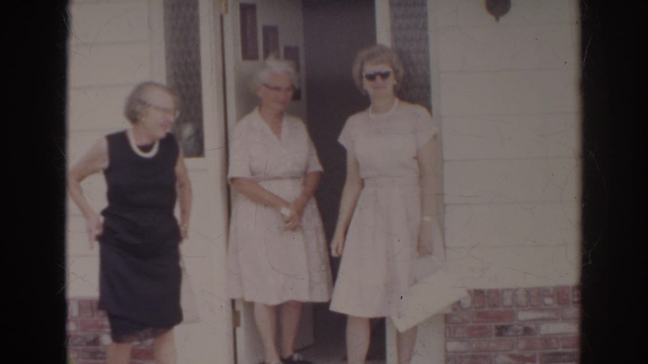 Two women remain by the doorway while another woman moves out of frame.