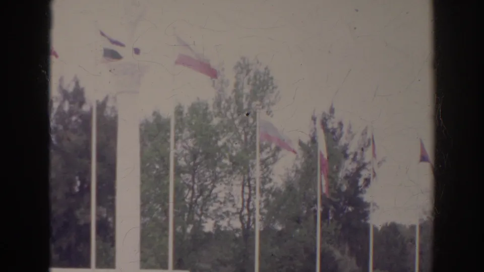 1966 Norfolk, Virginia home-movie view of flags, tree canopy, and a white monument or fountain in a public park setting.