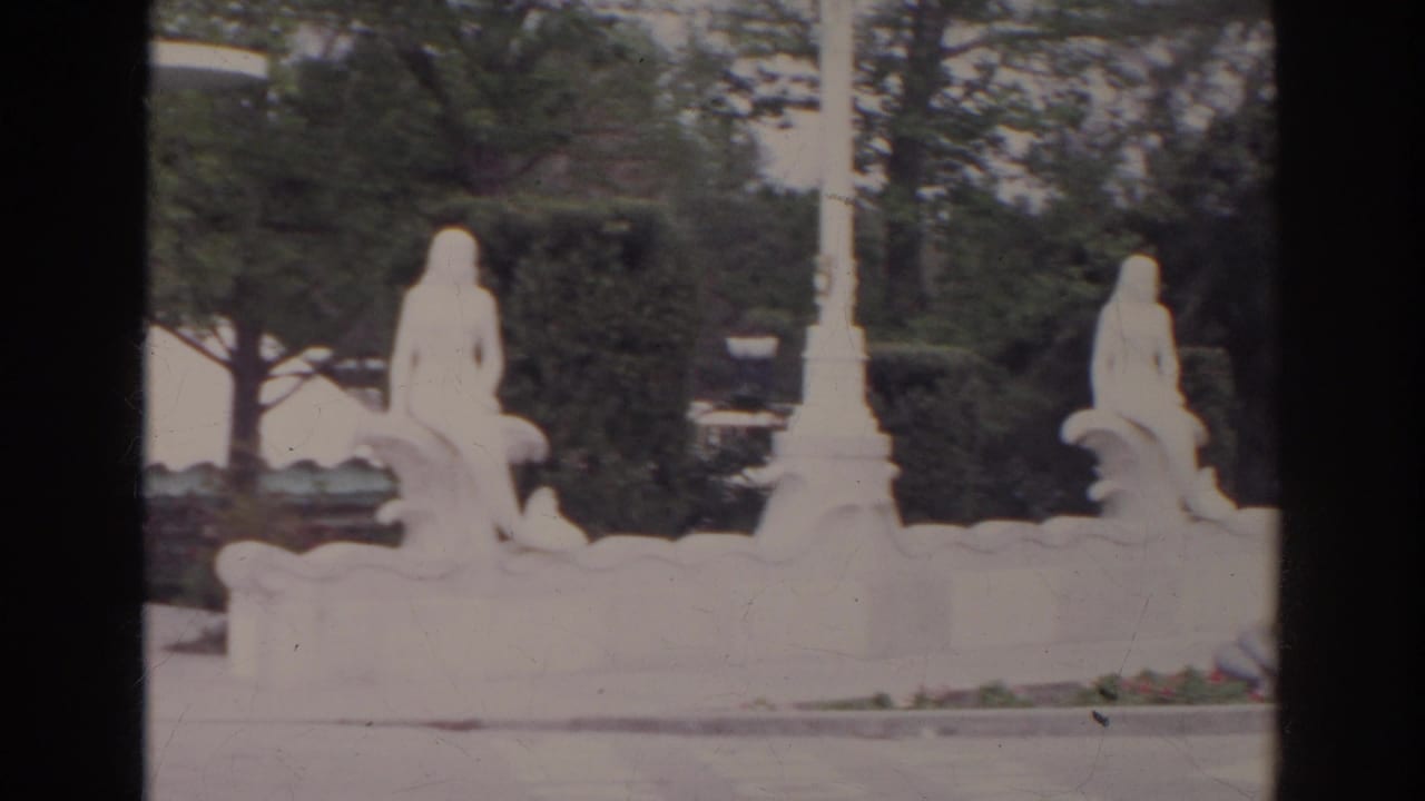 1966 Norfolk frame showing a white ornamental fountain with seated classical figures set among hedges and trees.