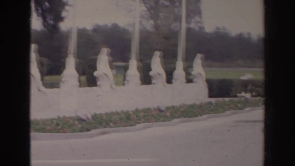 A second 1966 frame shows the statue row continuing past tall posts, with trees and roadway behind.