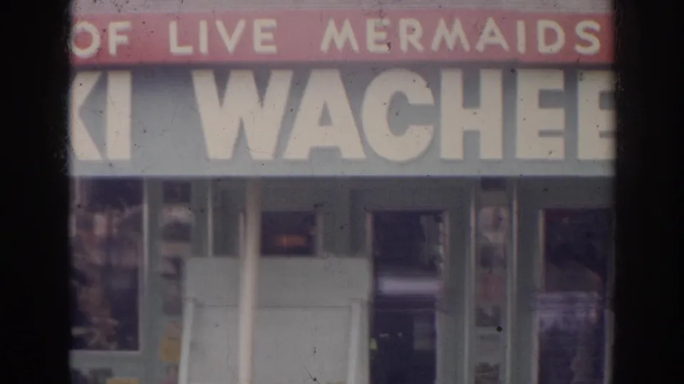 1966 Norfolk Weeki Wachee storefront detail with red live mermaids sign band, large lettering, display windows, and doorway openings.
