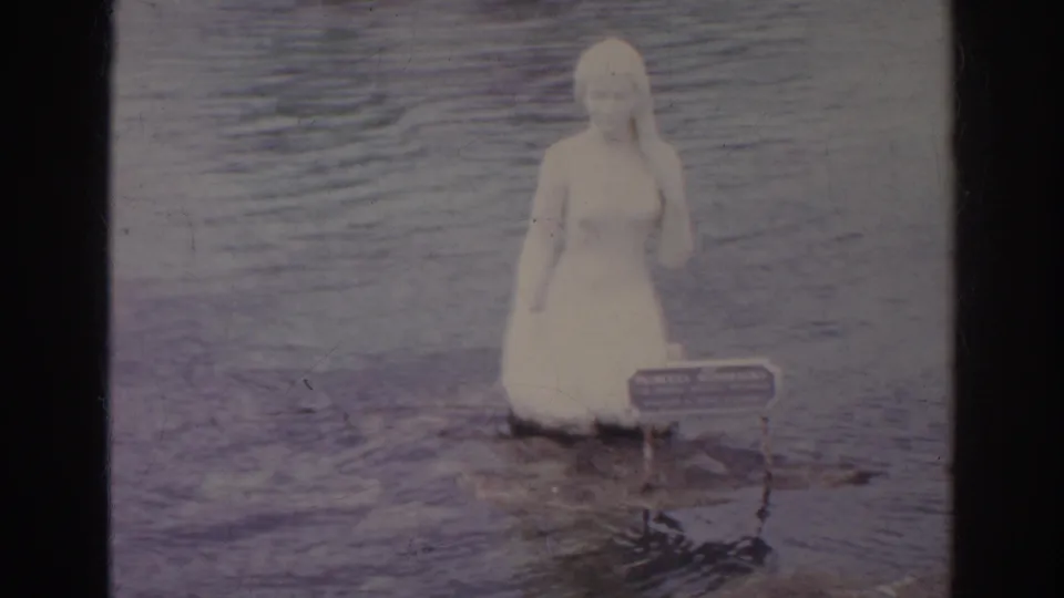 Final 1966 Norfolk frame holds on the female figure statue in the water, with the small base sign visible through faded 8mm color.