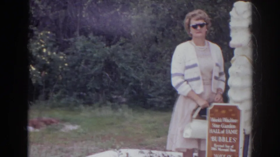 A woman in sunglasses stands beside a white seahorse statue and a Weeki Wachee Star Garden Hall of Fame sign.