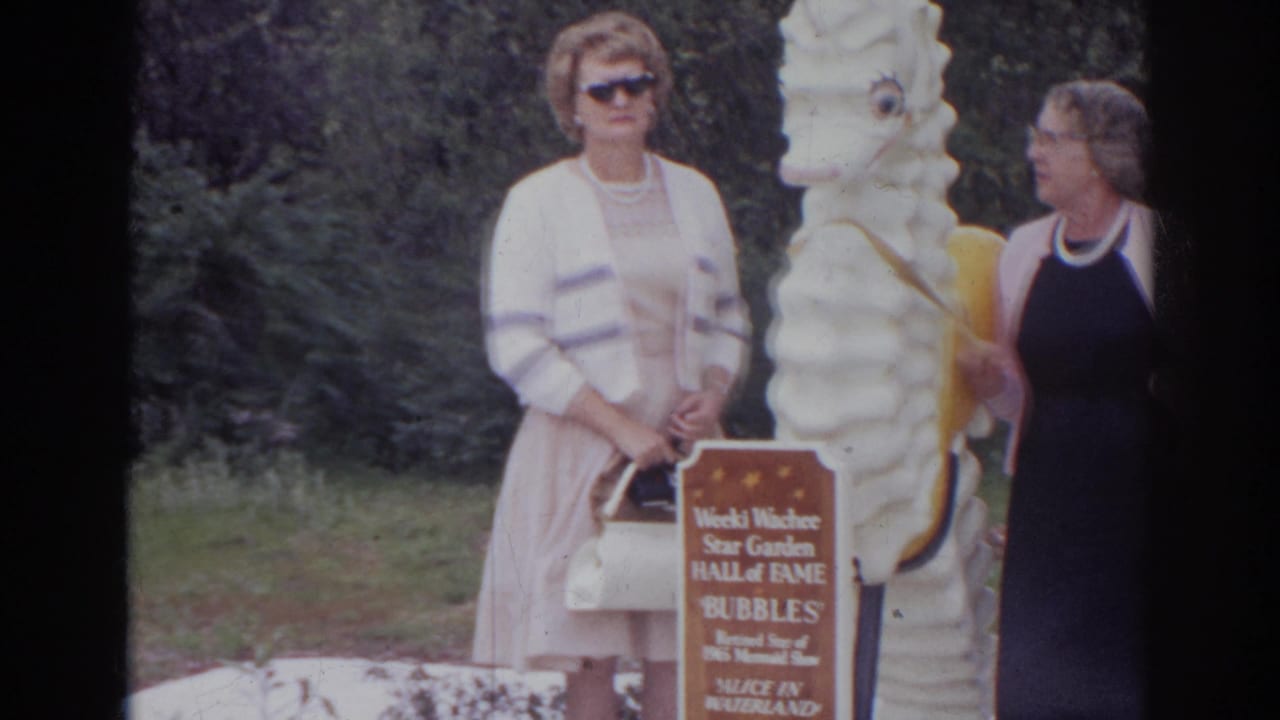 Two adult women in 1960s attire pose by a white seahorse statue and Weeki Wachee Star Garden Hall of Fame sign.