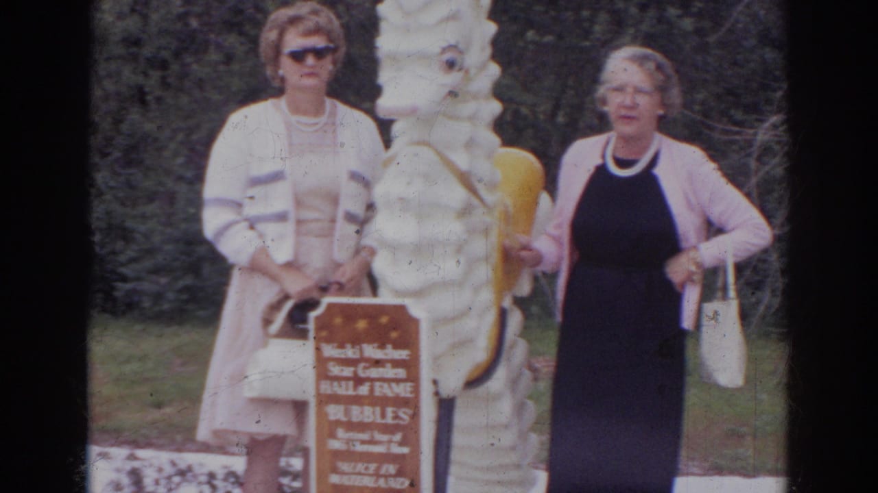Two adult women stand near the white seahorse statue and Bubbles sign at the Weeki Wachee attraction grounds.