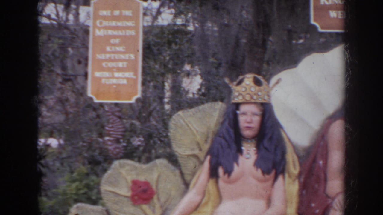 Costumed adult in a crown poses at the King Neptune's Court display with shell-like props and attraction signage visible.
