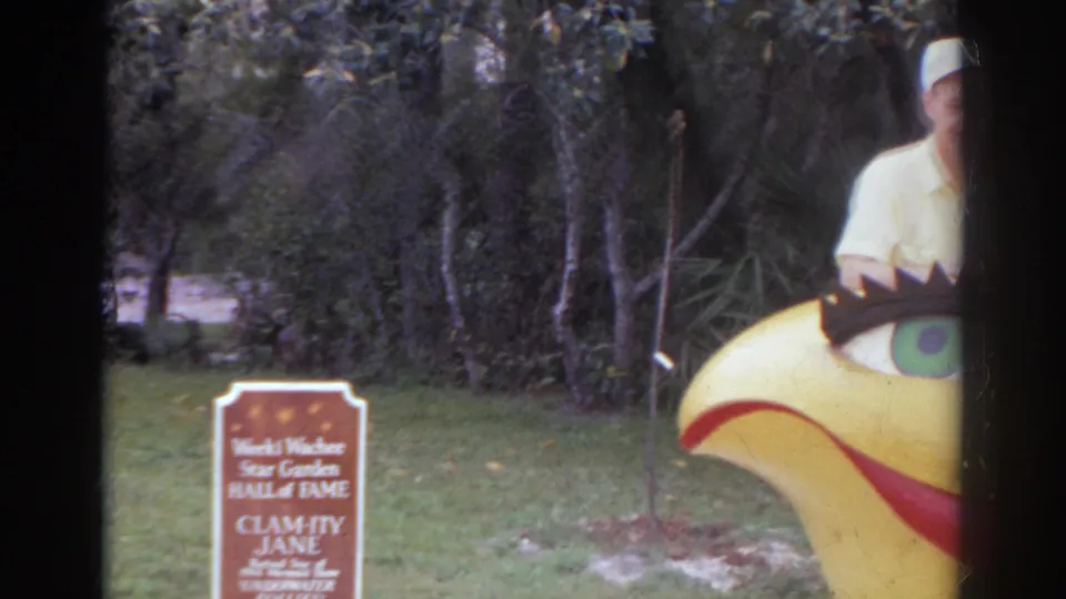 A Hall of Fame sign for Calamity Jane appears beside a yellow bird-like sculpture, with a partial adult figure at the frame edge.