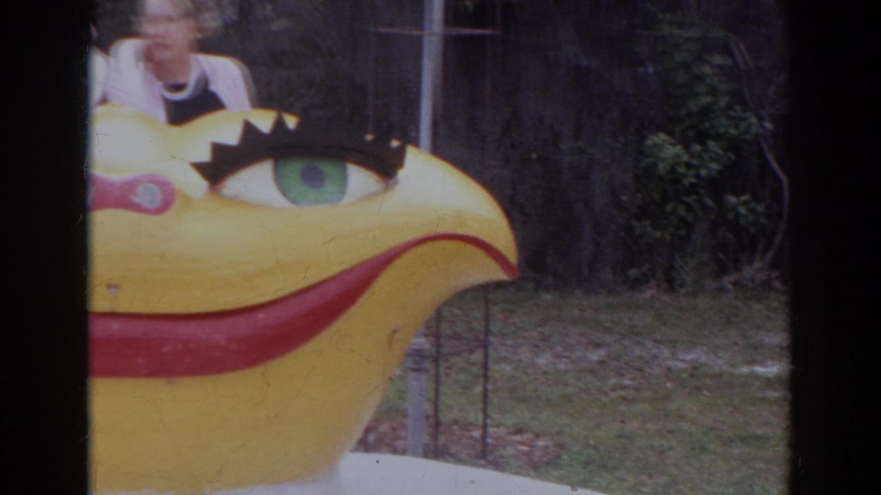 The camera drifts across the yellow smiling sculpture, with one adult partly visible above it in the Norfolk footage.