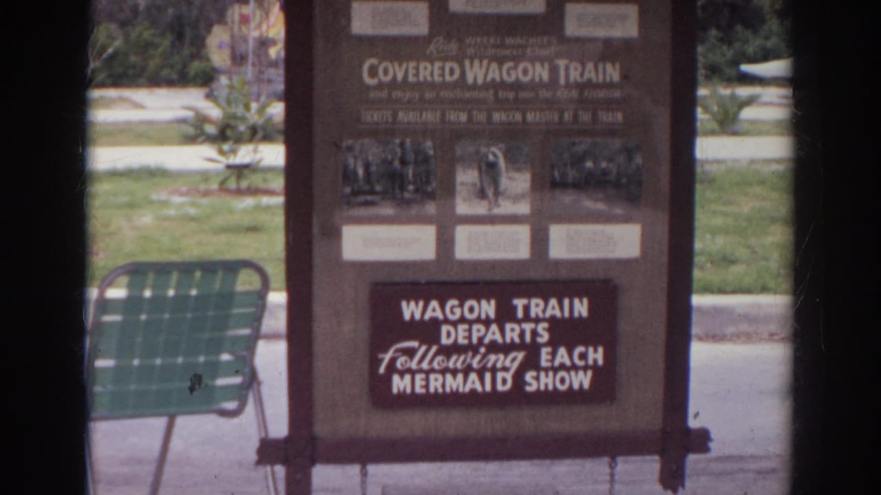 Norfolk, Virginia 1966 home-movie frame showing a Covered Wagon Train attraction sign and nearby green metal chair.