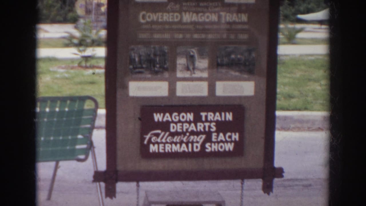 Norfolk, Virginia 1966 frame of a park sign for the Covered Wagon Train, partly framed by dark film borders.