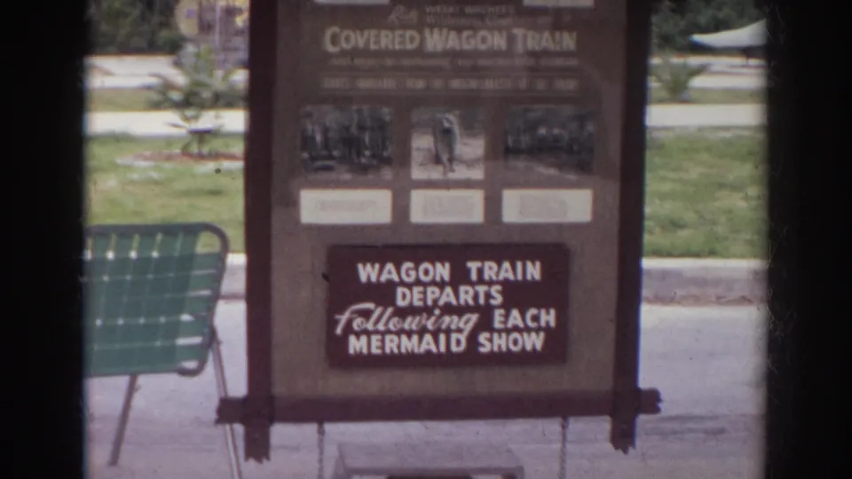 Norfolk, Virginia 1966 frame of a park sign for the Covered Wagon Train, partly framed by dark film borders.