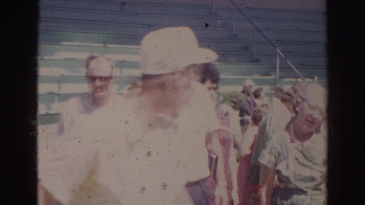 Spectators at the 1966 Norfolk natatorium sit or stand near bleachers, with faces, summer shirts, hats, and sunglasses visible.