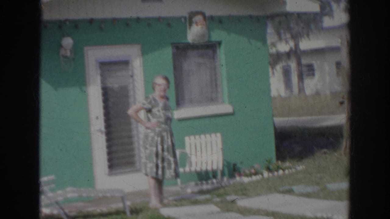 In the final frame, the woman stands with a hand on her hip near the green Norfolk house and yard furniture.