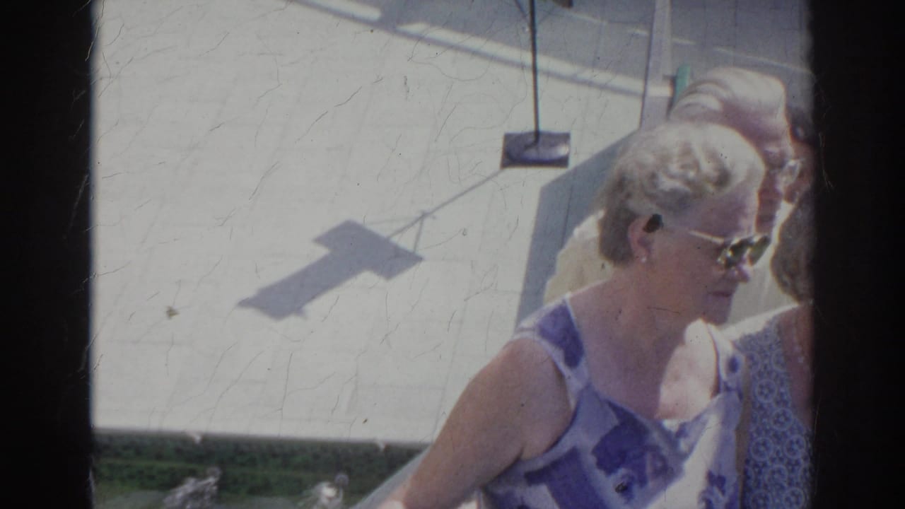 Older women walk outdoors on a bright paved surface, one wearing sunglasses.