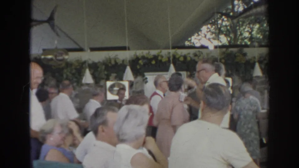 Norfolk, Virginia 1966 home-movie frame of older guests seated and standing at a mixer in a decorated interior.
