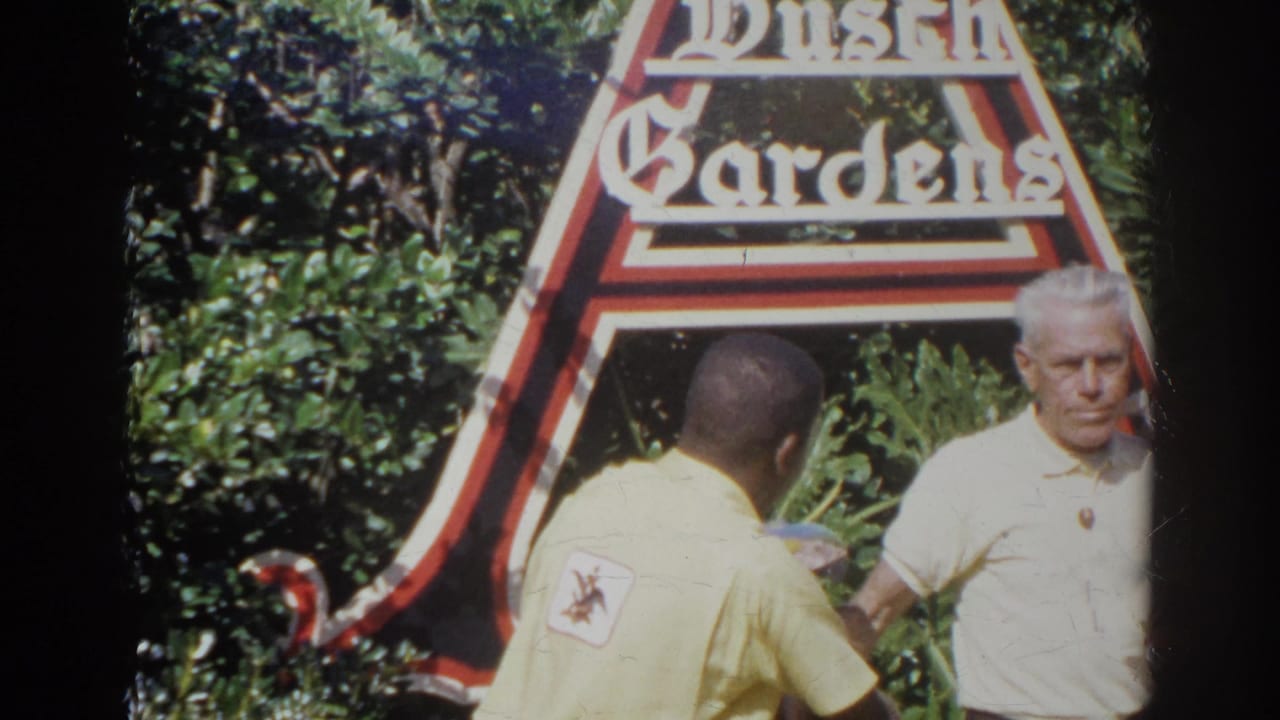 Park employee faces a man in a white shirt near the Busch Gardens sign.