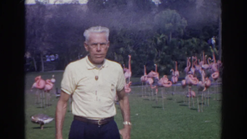 A front-facing visitor portrait shows the man centered against flamingos and garden landscaping in Norfolk, Virginia.