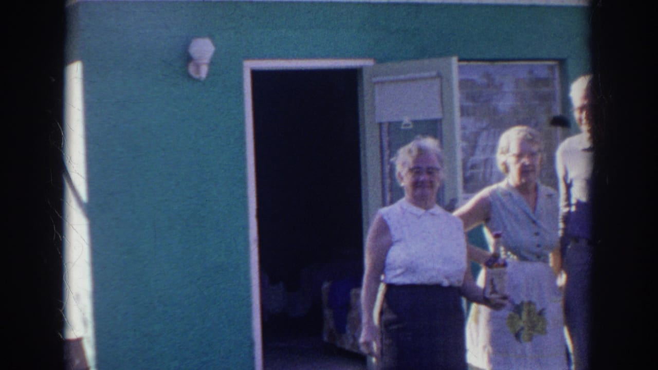 Three adults and a partly visible fourth person stand outside a green building in supported 1966 Norfolk home-movie footage.